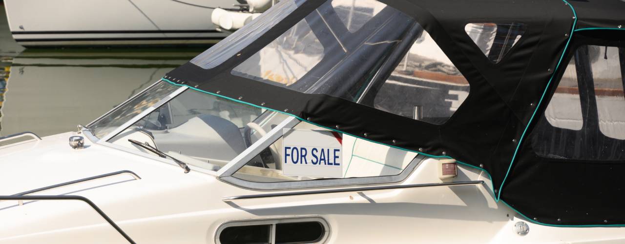 For Sale sign on a cruiser boat featuring a white background with bold, blue lettering indicating the boat is for sale.