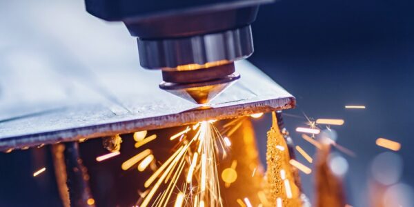 A CNC laser machine cutting a steel sheet. Orange sparks are flying off from the laser contact point.