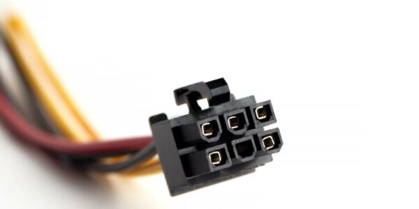 The black plastic casing of the head of a six-pin electrical connector in focus, the connector's wires blurred in the background.