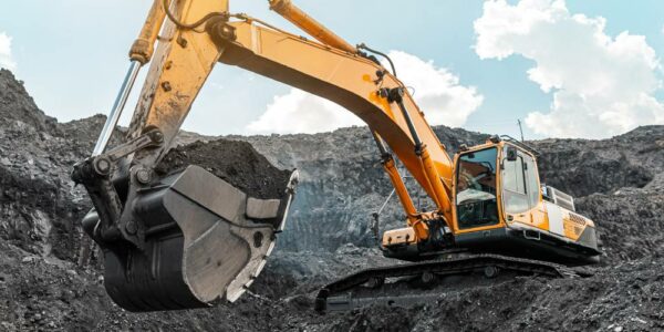 A large excavator stands on the top of a hill at a mining quarry. It carries coal and other minerals in its large bucket.