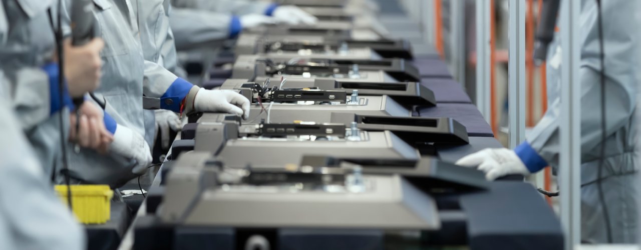 A production line with workers on both sides. They are all doing the same task to prepare a product for packaging.