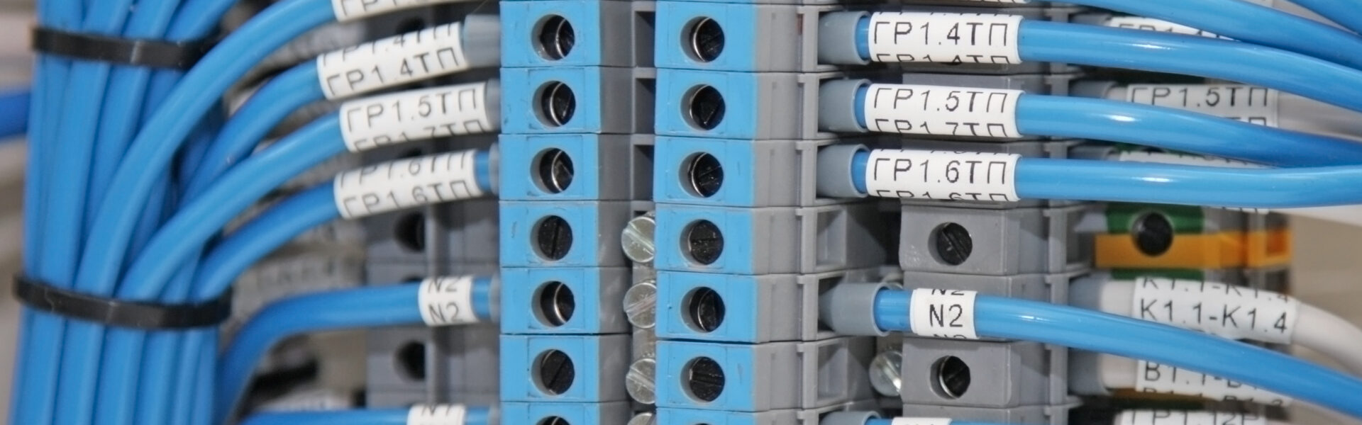 An electrical wire terminal with numerous blue electrical wires connected with white markings of letters and numbers.