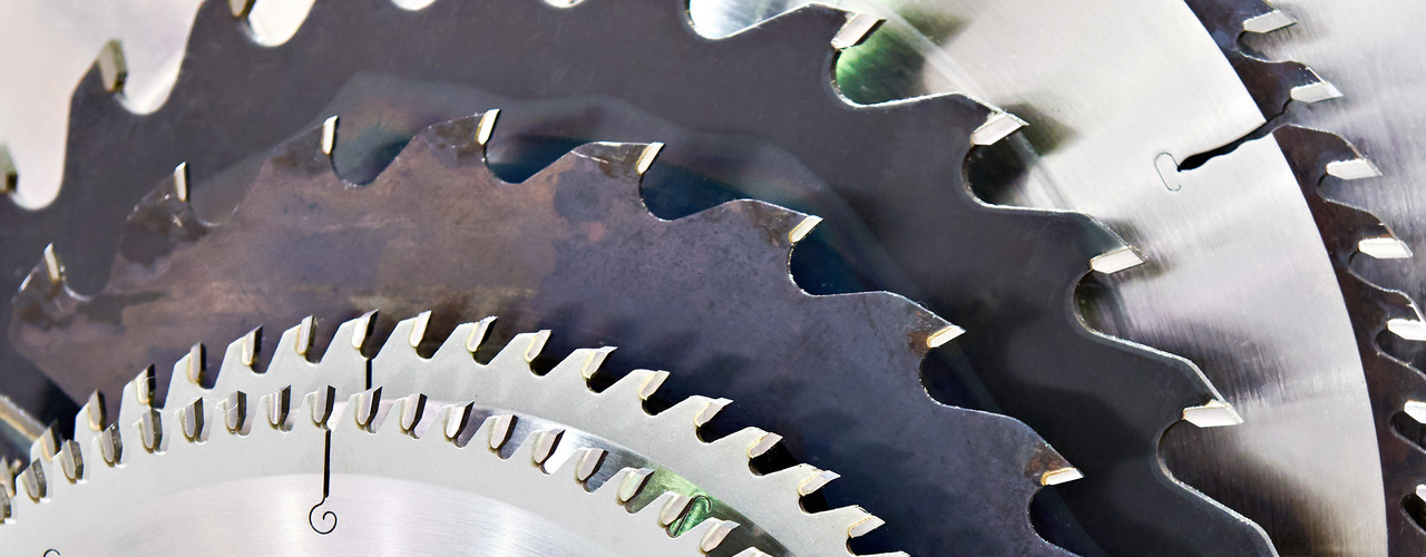 A line-up of saw blades of various sizes and shades of grey. The saws decrease in size as the stack progresses.