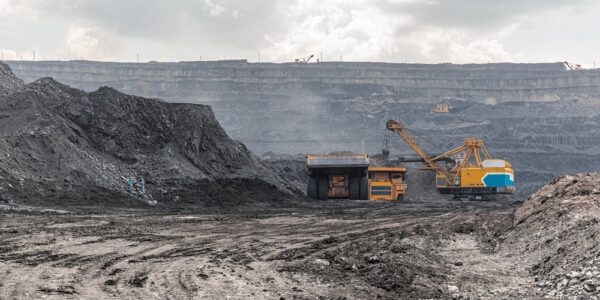 A panoramic view of an open-pit coal mine with a large yellow truck loading anthracite coal for transport from a quarry.