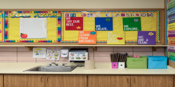 A corner of a classroom with colorful decorations on the wall above a counter. The decorations display words of encouragement.