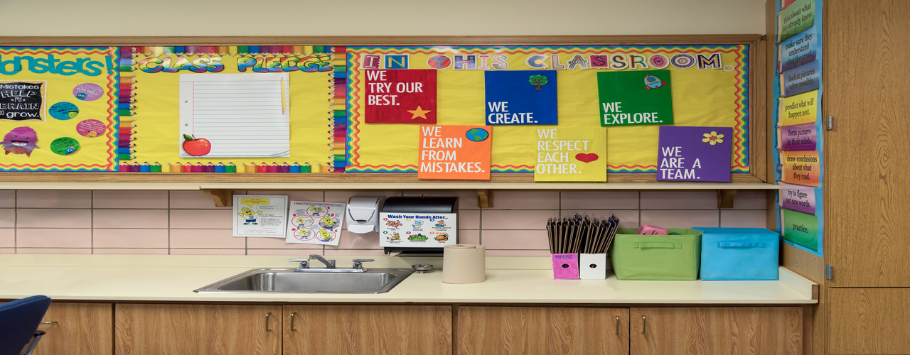 A corner of a classroom with colorful decorations on the wall above a counter. The decorations display words of encouragement.