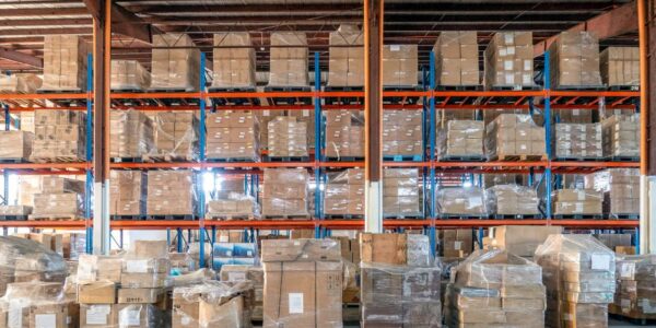 A view of a warehouse racking system with product packaged on pallets and wrapped in plastic wrap.
