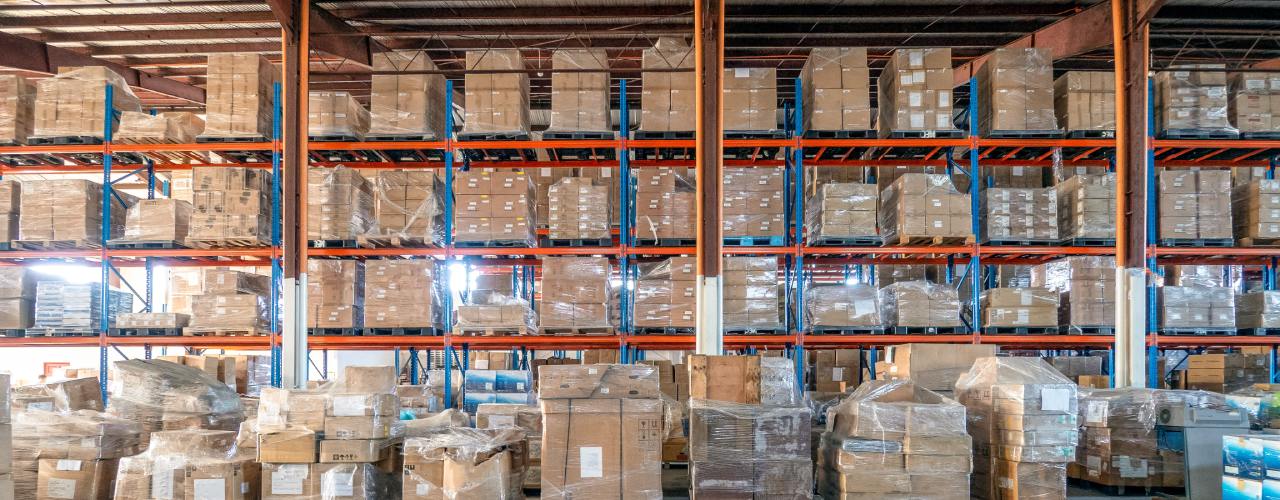 A view of a warehouse racking system with product packaged on pallets and wrapped in plastic wrap.