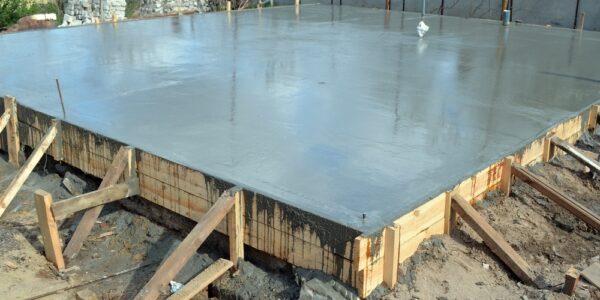 A freshly-poured foundation for a home with timber formwork and metal reinforcement on a construction site.