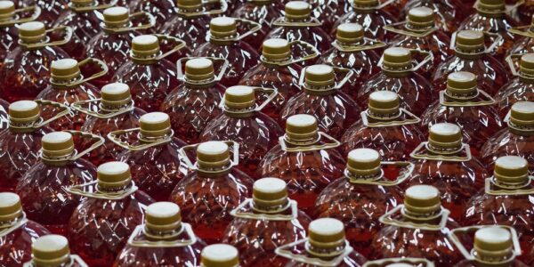 A close-up of a huge assembly of clear plastic bottles with golden caps and handles filled with red liquid.
