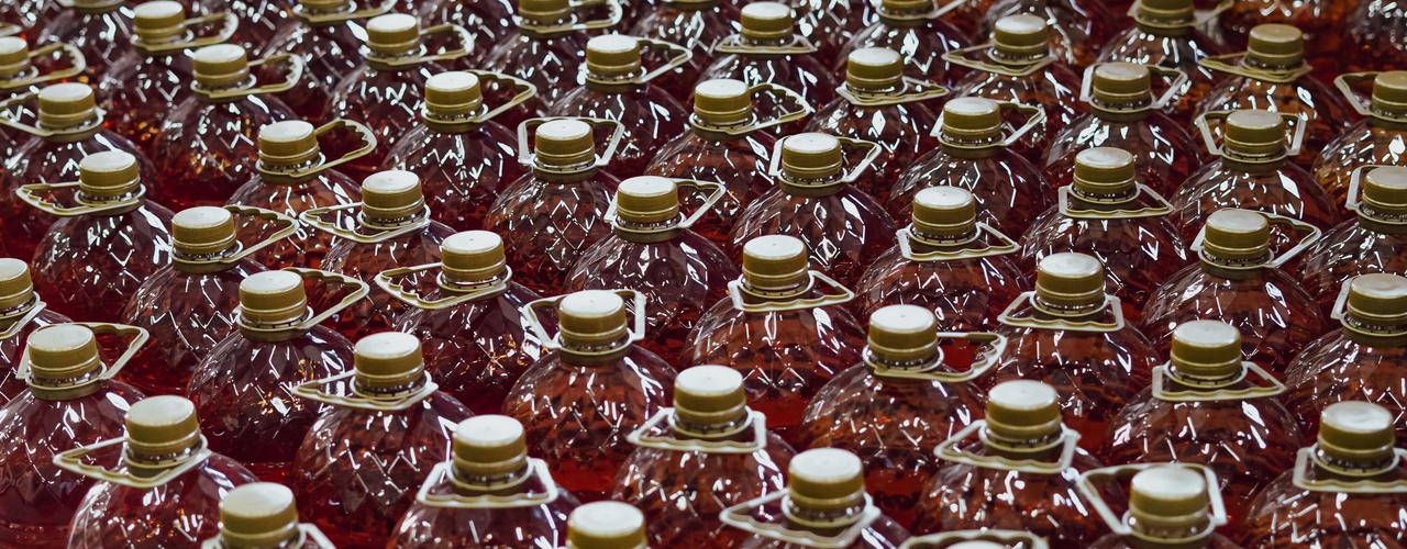 A close-up of a huge assembly of clear plastic bottles with golden caps and handles filled with red liquid.