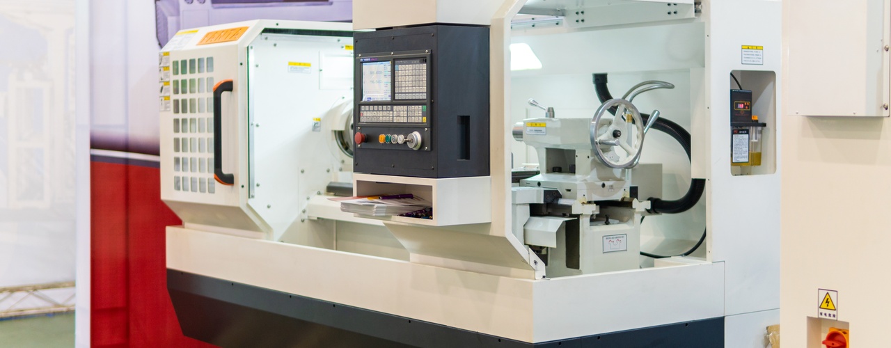 A large CNC machine is black and white. It has large windows to observe the inside of the machine.