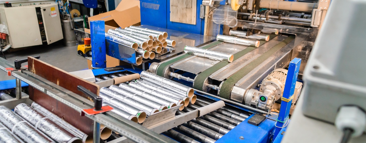 A close-up of a roller production line in a manufacturing facility transporting aluminum metal sheet rolls.